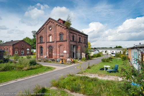 Elektrozentrale, Waschkaue der Zeche Lothringen III - Bochum-Gerthe - Die Zechen errichteten zur Unterbringung in der Regel Barackenlager. Das Lager der Schachtanlage III entstand 1940 und 1941 als eines von vier Lagern der Zeche Lothringen. Nach dem Krieg wurden die Baracken in kleinere Wohneinheiten aufgeteilt. 1983 entwickelte sich ein studentisches Wohnprojekt; das die Gebäude in den heutigen Zustand versetzte. Trotz dieser Umbauten ist die Grundstruktur des Lagers weitgehend erhalten; es kann damit als eines der wenigen noch vorhandenen Beispiele seiner Art in Deutschland gelten. Foto © Dietrich Hackenberg