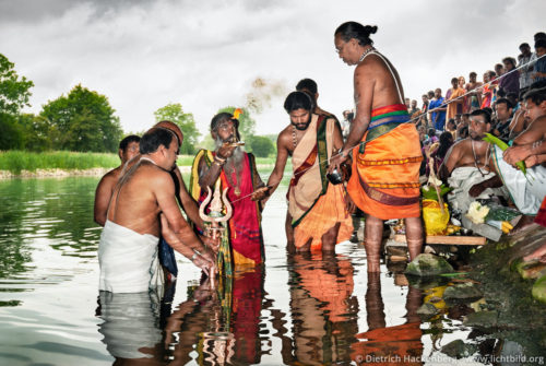 Priester Paskarakurukkal weiht das Wasser des Datteln-Hamm-Kanals- Hindutempel, Hamm-Uentrop - Vorbereitung für das rituelle Bad im Kanal unter der Autobahnbrücke der A2. Über eine Schnur wird das Wasser durch die Göttin geweiht, bevor die Männer in den Kanal steigen. Foto © Dietrich Hackenberg