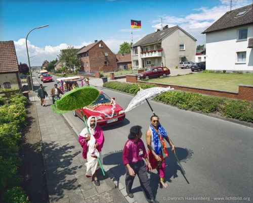 Umzug mit Göttin durch ein Wohngebiet mit Deutschlandfahne - Hindutempel, Hamm-Uentrop - Die Göttin Sri Kamadschi Ampal wird durch die Vororte von Hamm gefahren, bevor sie in den neugebauten Tempel einzieht. Sie soll Menschen und Umgebung kennenlernen. Foto © Dietrich Hackenberg