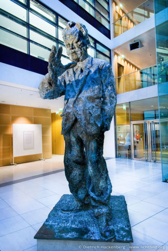 Willy-Brandt-Skulptur von Rainer Fetting - Willy-Brandt-Haus, Wilhelmstr. 141, 10963 Berlin - Foto © Dietrich Hackenberg - Von Februar bis Juni 1937 hält sich der aus Deutschland nach Norwegen emigrierte Willy Brandt in Spanien auf. Er sendet regelmäßig Berichte über an seine politischen Freunde in Paris, dem Sitz der SAP (Sozialistische Arbeiterpartei) Auslandsleitung, sowie an skandinavische Arbeiter und Gewerkschaftszeitungen. Das norwegische Spanien Komitee informiert er über wirksame Hilfsmöglichkeiten für die Bevölkerung. […] Die Lage in Katalonien war verwirrend. Dass es kaum etwas zu Essen gab und der Hunger mit Rotwein, bestenfalls Oliven betäubt werden musste, das es unwürdig war Trinkgeld zu geben und Bedienung durch Händeklatschen herbeizurufen, und allerorts ein ‚Sozialismus der unmittelbaren Produzenten’ angepriesen wurde, nun ja daran gewöhnte man sich rasch. Aber sonst? Es brauchte einige Zeit bis ich zu verstehen begann. […] Willy Brandt über seinen Aufenthalt im Spanischen Bü rgerkrieg In: Links und frei. Mein Weg 1930–1950. Hamburg 1982 […]Lehrreiche, doch überwiegend unglückliche Monate.[…] So fasst Willy Brandt seine Erfahrungen zusammen. In seinen Lebenserinnerungen ergänzt er: […] Nach den Monaten in Berlin und in Barcelona fühlte ich mich meiner Sache sicher und war nicht länger ein Suchender. […]