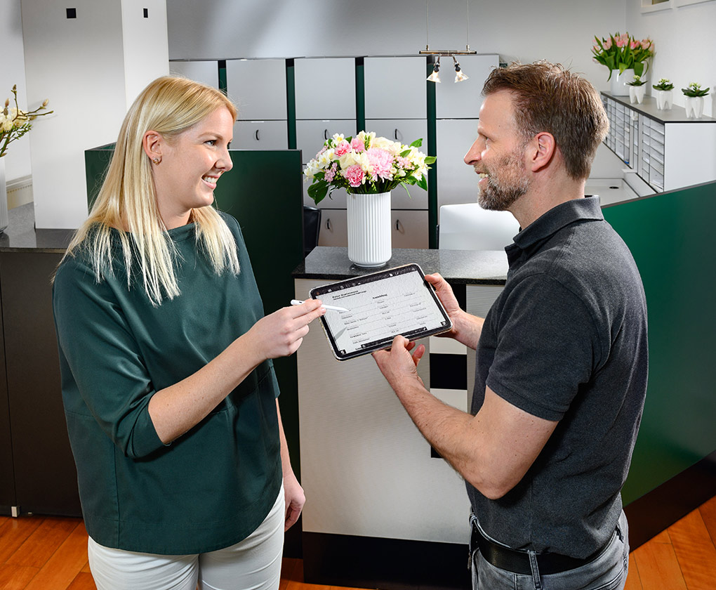 Erster Termin - Helferin und Patient bei der Online-Anamnese mit einem Tablet