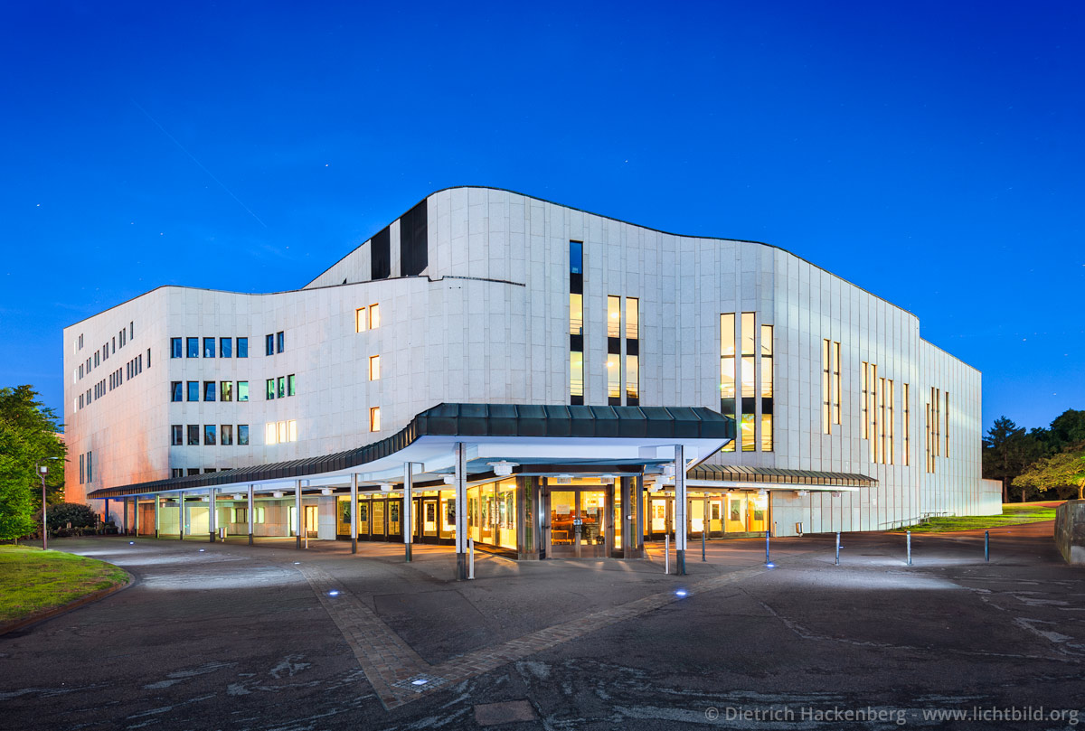 Front Aalto-Theater bei Nacht, Essen Das Aalto-Theater ist das Opernhaus der Stadt Essen. 1959 hatte sich eine Jury einstimmig für den Entwurf des finnischen Architekten Alvar Aalto entschieden. Erst 1983, sieben Jahre nach dem Tode Aaltos, kam es zum ersten Spatenstich. Das Opernhaus wurde am 25. September 1988 eröffnet. Der Bau erinnert mit seinen organisch fließenden Grundformen an finnische Landschaften. Foto © Dietrich Hackenberg