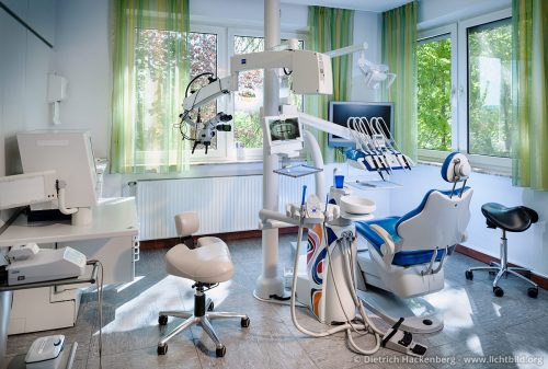 Ein Behandlungszimmer ohne Menschen wirkt normalerweise zu technisch und kühl. Hier mildern das Lichtspiel der Sonne und das Grün der Bäume vor dem Fenster diesen Eindruck.
